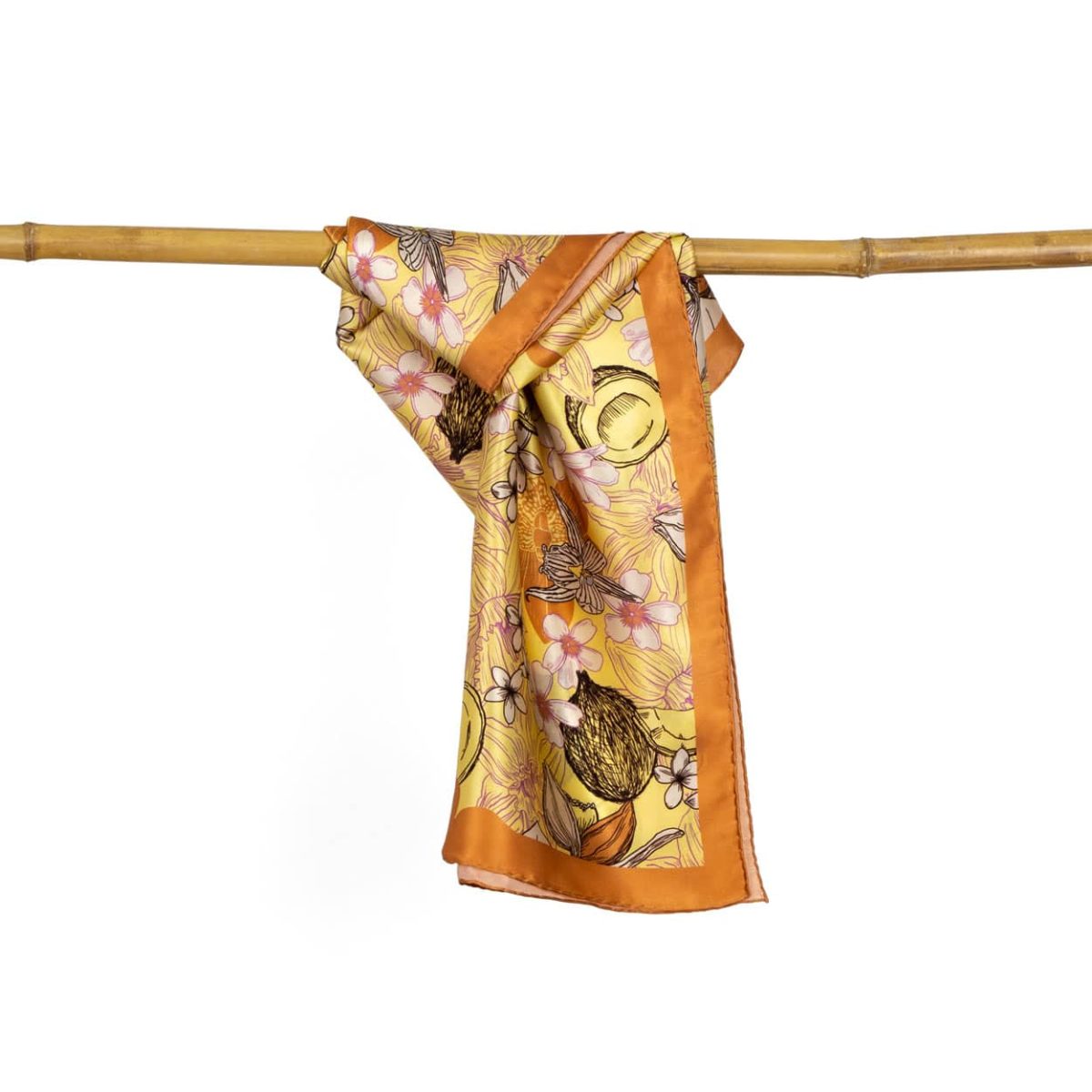 Mustard color square silk scarf with flower and coconut print hanging on bamboo cane